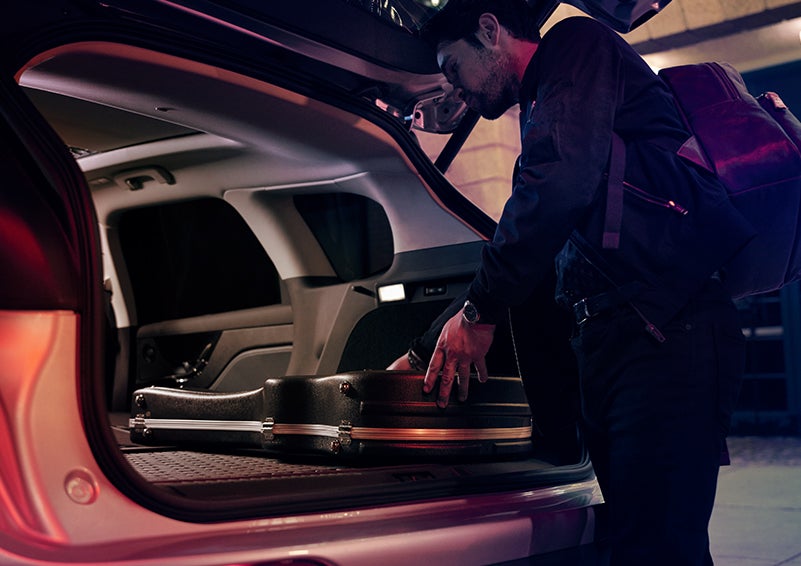 A man is shown loading cargo into the rear of a 2023 Lincoln Corsair® SUV with the second-row seats folded flat. | All Star Lincoln in Prairieville LA